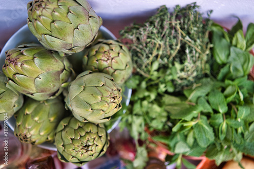 Aerial close-up of half a dozen fresh artichokes and vegetables. Healthy, ecological and healthy food photo