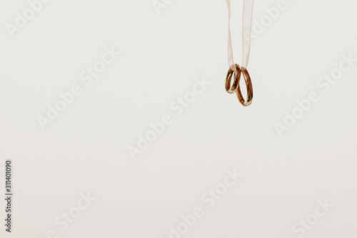 Two golden wedding rings hanging on a ribbon, isolated on white background