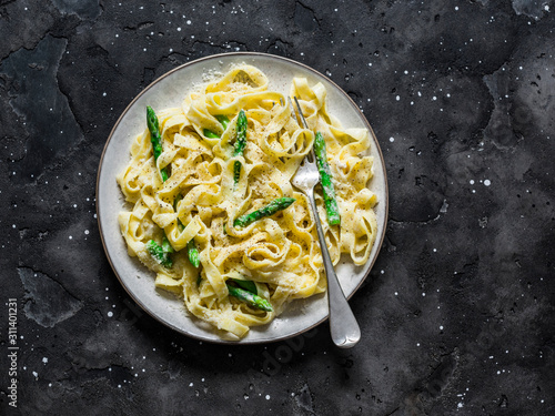 Mascarpone cheese sauce fettuccine pasta with asparagus on a dark background, top view photo