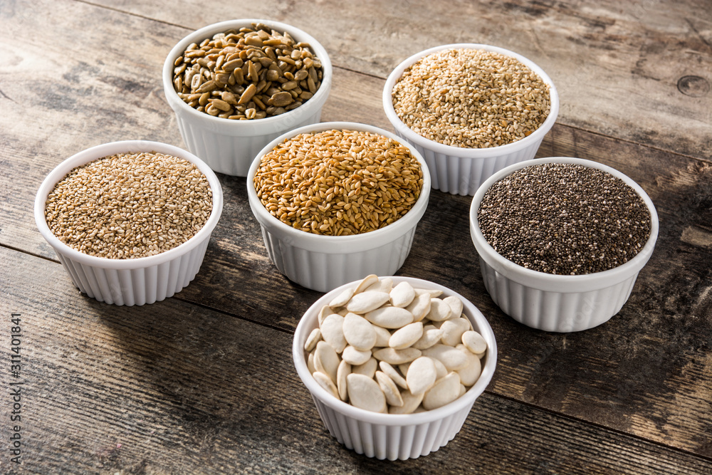 Assortment of different seeds in bowl on wooden table. Pumpkin, linen, chia, sunflower, and sesame seeds Assortment of different seeds in bowl on wooden table. Pumpkin, linen, chia, sunflower, and sesame seeds