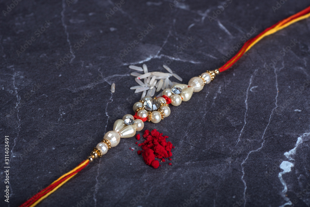 Raksha Bandhan : Rakhi with rice grains and kumkum on stone background ...