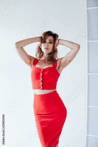 Portrait of a beautiful fashionable woman in a red dress in a white office © dmitriisimakov