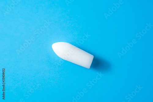 White suppositories for anal or vaginal use on blue background. Medical candles for treatment of Candida, thrush, hemorrhoids, inflammation and fever. Effective drug for timely treatment of diseases