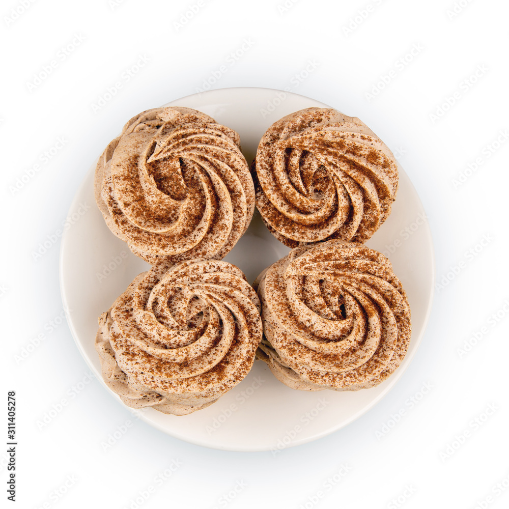 Four marshmallows, sprinkled with cinnamon and chocolate, lie on a white plate. Top view, isolated on a white background. Four marshmallows, sprinkled with cinnamon and chocolate, lie on a white plate. Top view, isolated on a white background.