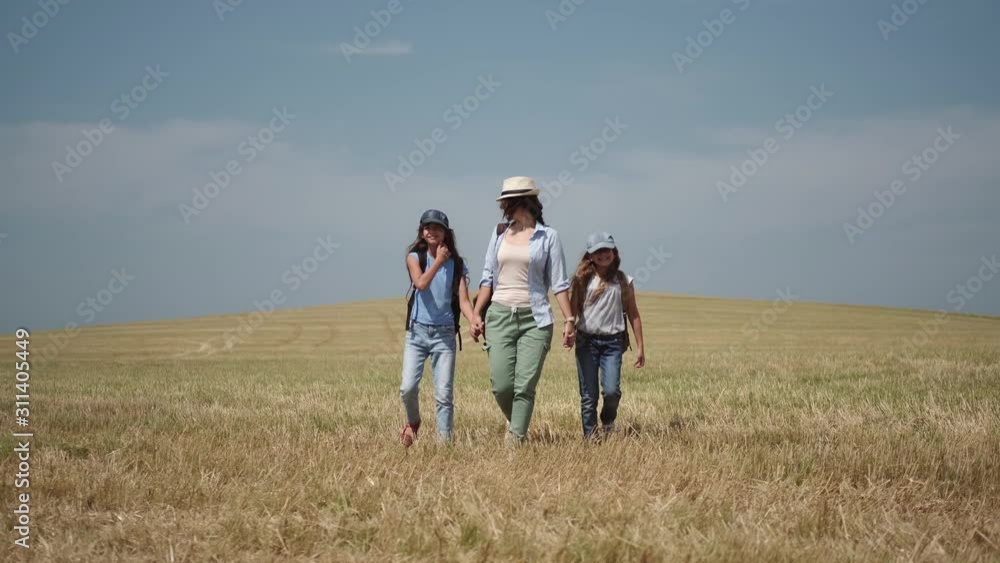family of travelers is walking on a hill. mother leads her young children on a hike. family of travelers is walking on a hill. mother leads her young children on a hike.
