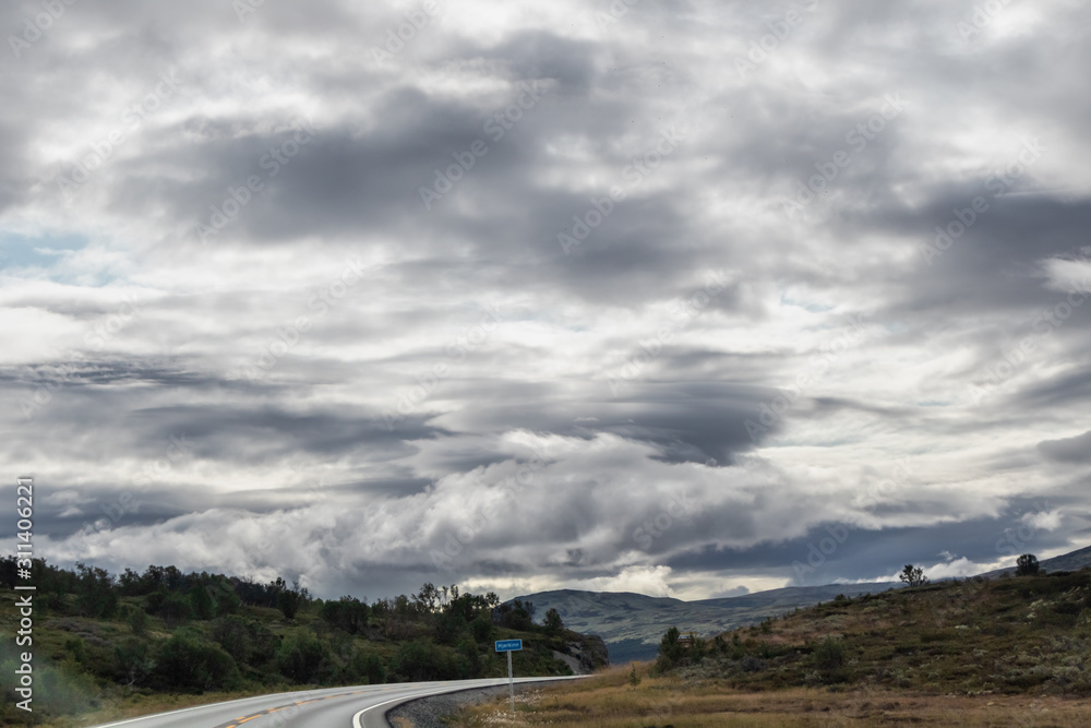 Mountains in Norway road epic scenic sky, way, clouds view. Traveling by car, driving nature tourism. Dramatic skyscape northern scandinavian sky