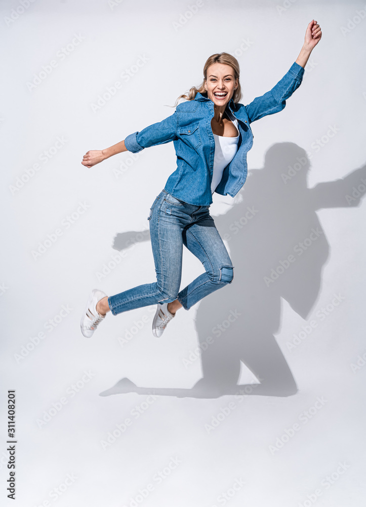 Full length portrait of a cheerful happy woman jumping and looking to the camera isolated over white background