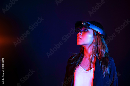 Colorful portrait of young asian business women try augmented and virtural reality glasses hololens in the lab room. Mixed reality future technology concept. Feminism power in world technology.