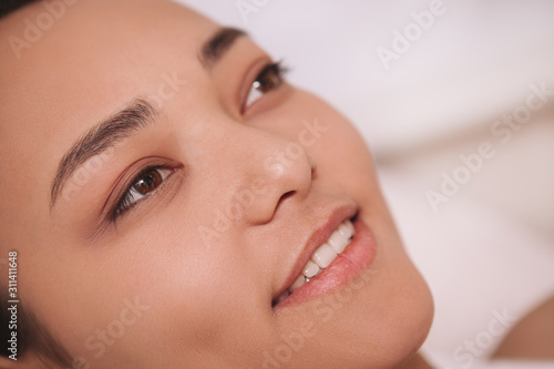 Close up of the face of a happy beautiful Asian woman smiling, resting at spa resort. Relaxation, wellness concept