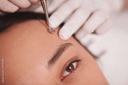 Cropped sot of Asian woman having her skin cleaned by professional cosmetologist, using blackhead remover