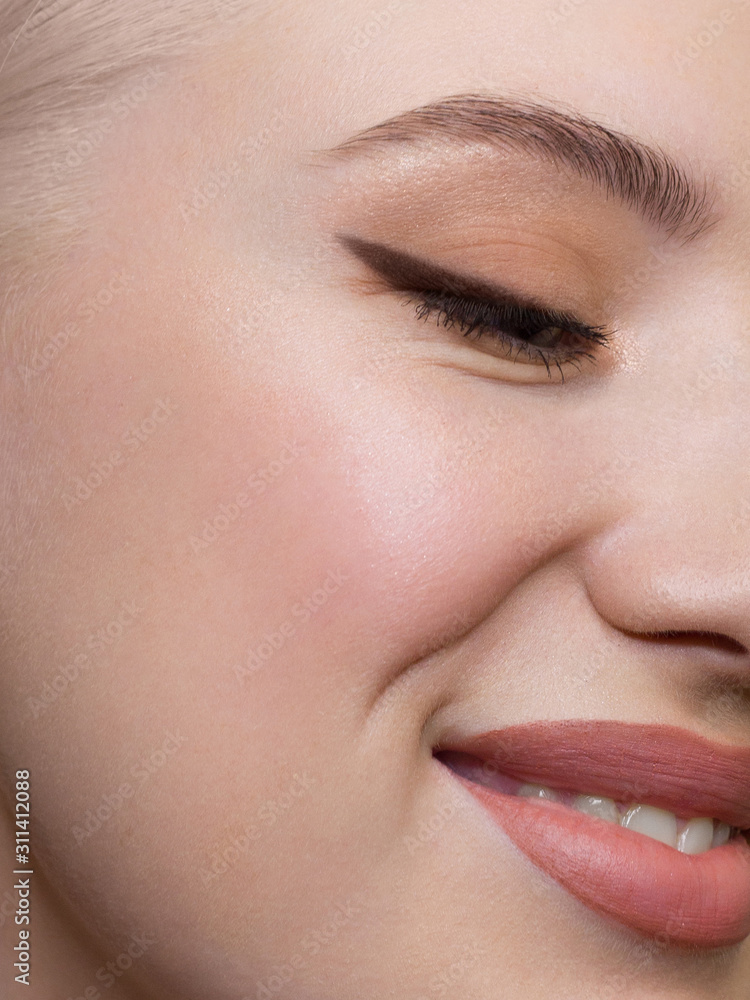 Fototapeta premium Half a beauty portrait with beautiful fashionable day make-up, black liner on eyes and extremely long eyelashes. natural lipstick on the sexy lips. Cosmetology and spa facial skin care