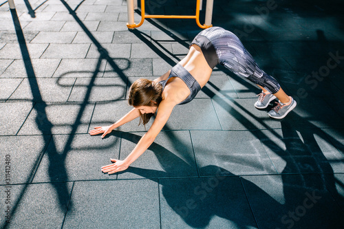 Woman doung stretching exercise on sportsground outdoors in morning. photo