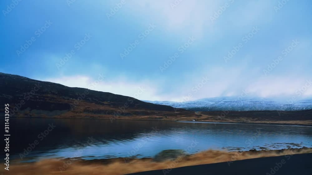 Driving on highway in Westfjords of Iceland during daytime next to blue lake. Driving on highway in Westfjords of Iceland during daytime next to blue lake.