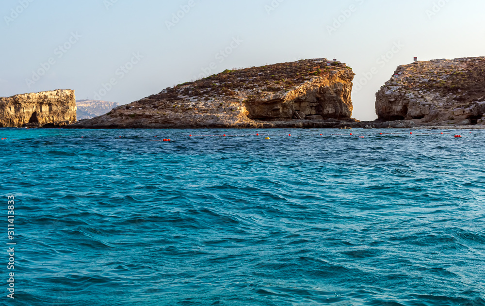 The Blue Lagoon at boat level with Cominotto island in background. It is an uninhabited Mediterranean island off the northern coast of Malta, near Comino island.