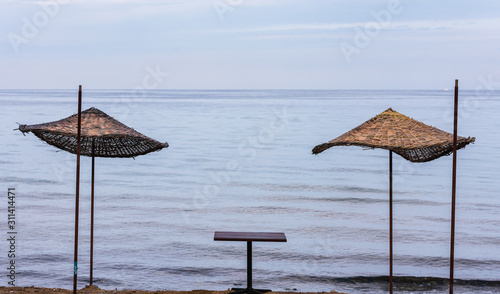 Umbrella on the beach. Dramatic seascape. Straw umbrellas and table on beach.