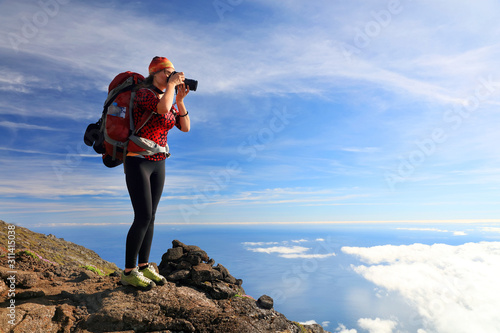Young girl trekking and taking photos on Pico volcano (2351m) on Pico Island, Azores, Portugal, Europe