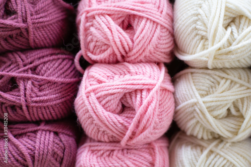 Multi-colored pink, lilac, white woolen threads in balls for knitting and handmade.