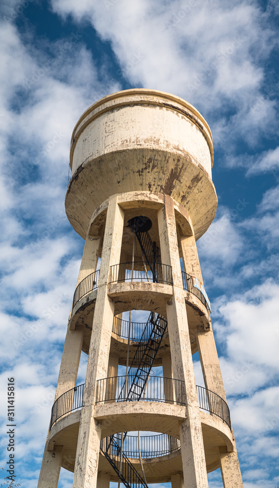 Old water tower. Vertical panoramic image. Clouds and dramatic sky in background. Old water tower. Vertical panoramic image. Clouds and dramatic sky in background.