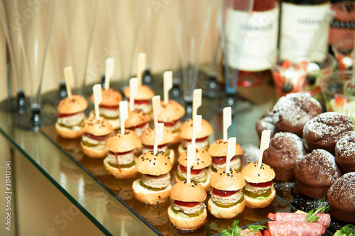 A tray with small burgers on the festive table.