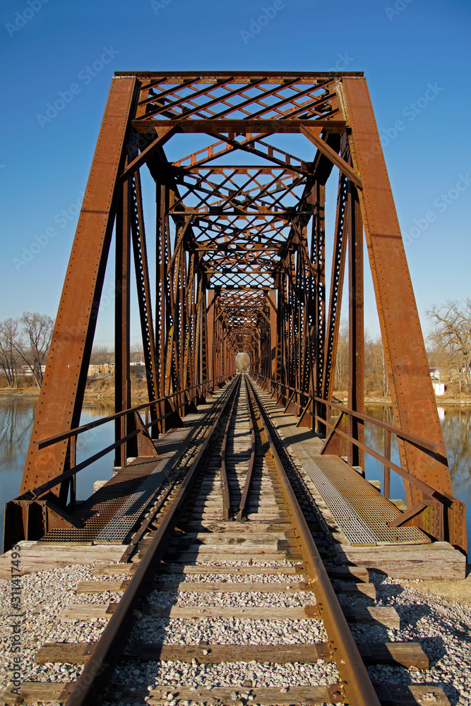 looking down the tracks of a rusty steel train bridge over the Wabash River in logansport Indiana