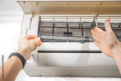 HVAC technician working on a capacitor part for condensing unit. Male worker or repairman in uniform repairing and adjusting conditioning system, diagnosting and looking for technical issues.