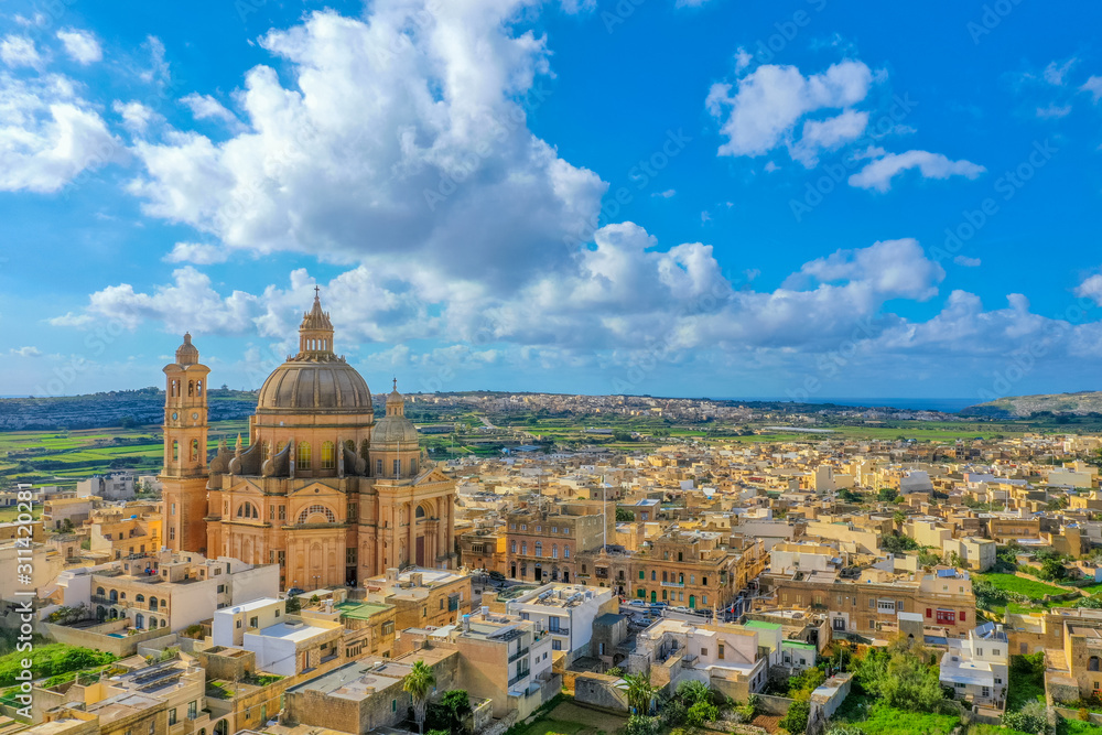 Aerial view oа St. John Baptist Church. Countryside of Gozo island, cloudy blue sky. Malta island 