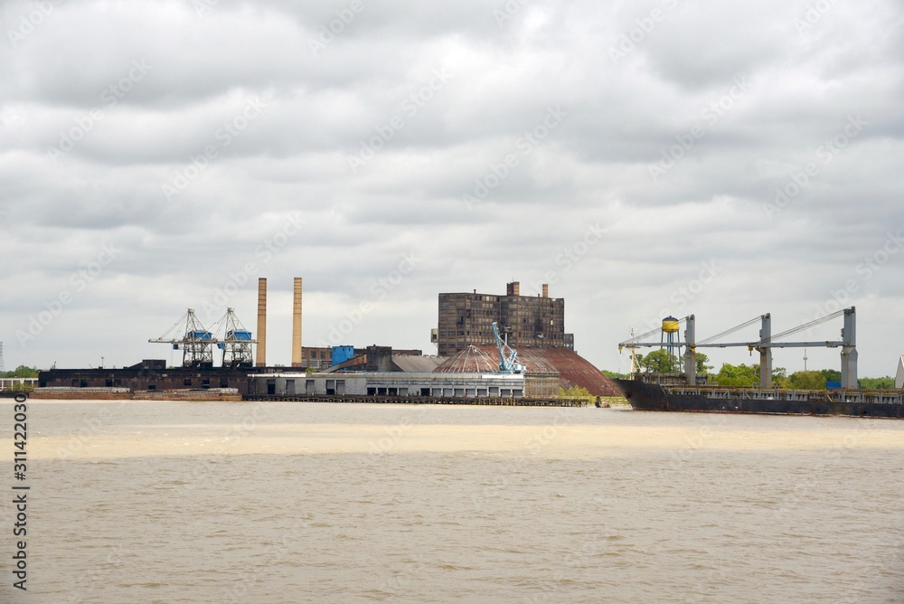 A freighter sits by a sugar factory on the Mississippi River waiting to be loaded