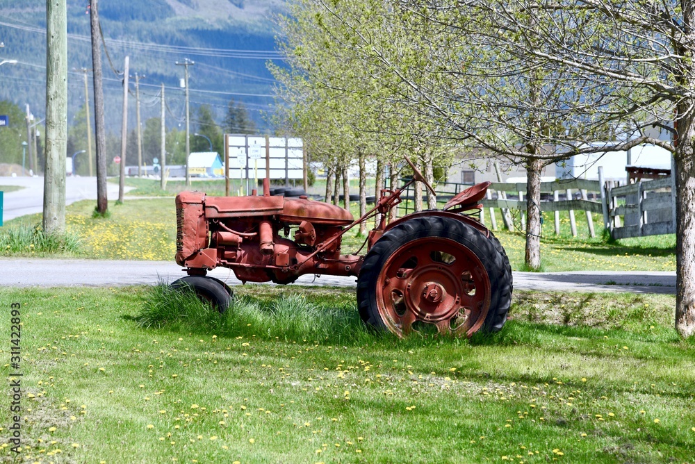 An old red tractor sits in a farm yard An old red tractor sits in a farm yard