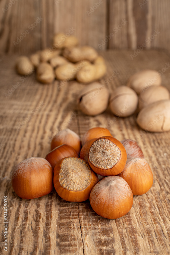 Inshell hazelnuts. Nuts mix on the old rustic wooden background. Food for man's and women health. Raw foods for vegetarians and vegans. Inshell hazelnuts. Nuts mix on the old rustic wooden background. Food for man's and women health. Raw foods for vegetarians and vegans.
