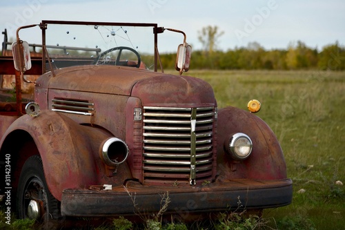 An old firetruck sits in a farmers field with its windshield full of bullit holes