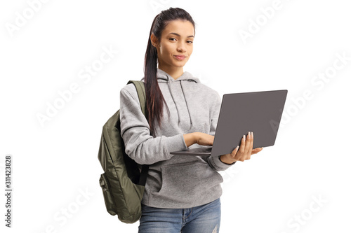 Cute female student holding a typing on a laptop and looking at the camera photo