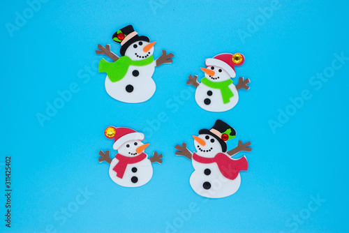 Funny snowmen in red and green scarves and black hats on a blue background