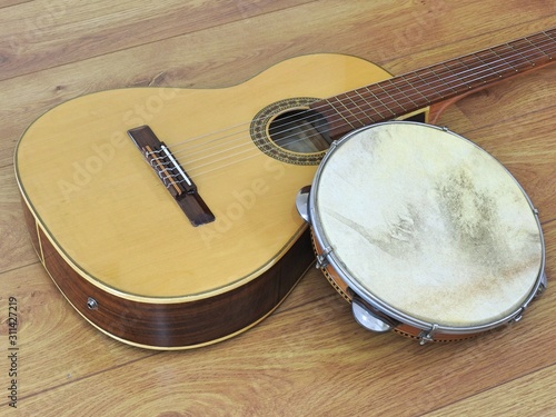 Close-up of an acoustic guitar and a pandeiro (tambourine), a Brazilian percussion musical instrument, on a wooden surface. They are widely used to accompany samba and choro, popular Brazilian rhythms
