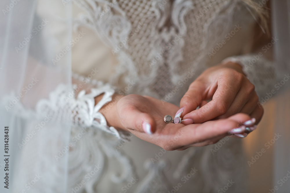 The bride holds the earrings in her hands before putting them on 2377. The bride holds the earrings in her hands before putting them on 2377.