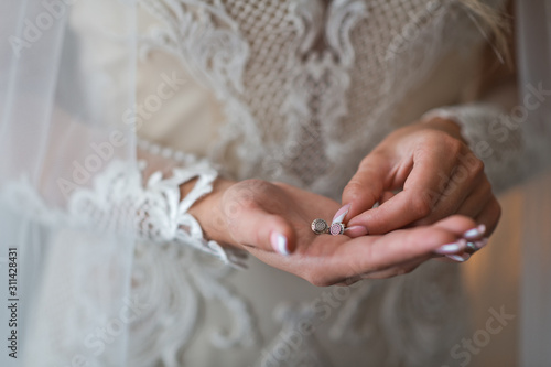 The bride holds the earrings in her hands before putting them on 2377.