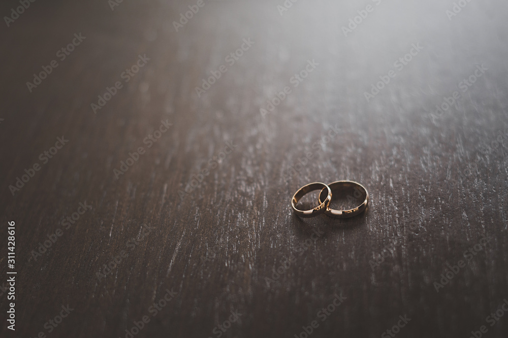 Two wedding rings on a dark wood table. Two wedding rings on a dark wood table.