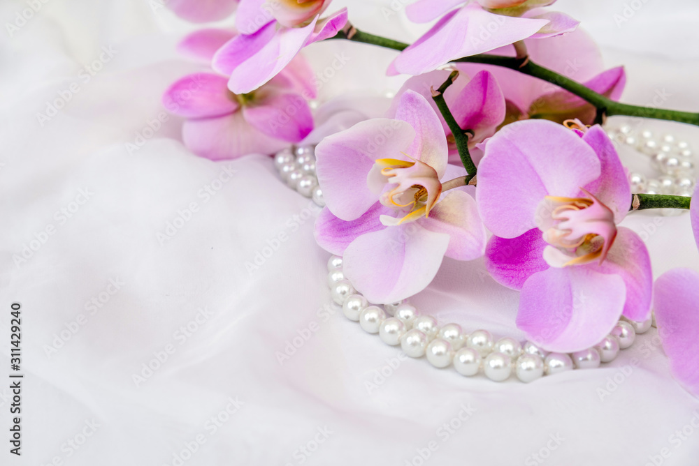 The branch of purple orchids on white fabric background The branch of purple orchids on white fabric background