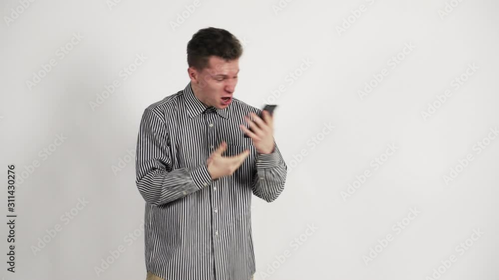 guy of the Caucasian appearance swearing on the phone. Angry and aggressive. Unhappy. Emotions. On a white background. guy of the Caucasian appearance swearing on the phone. Angry and aggressive. Unhappy. Emotions. On a white background.