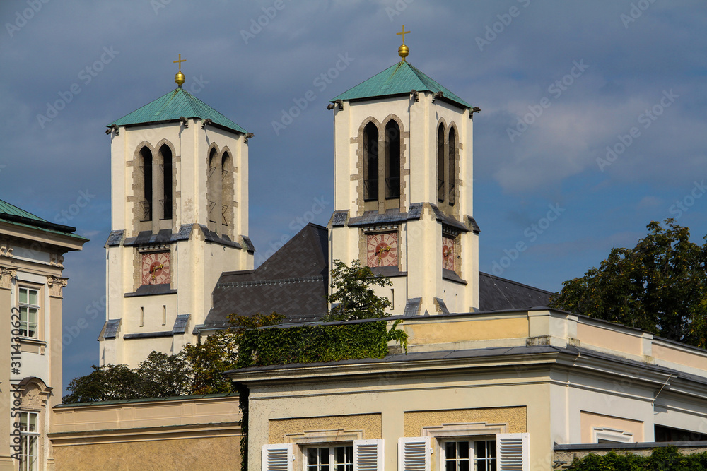 Double bell tower of the Catholic Church with a green roof against a cloudy sky