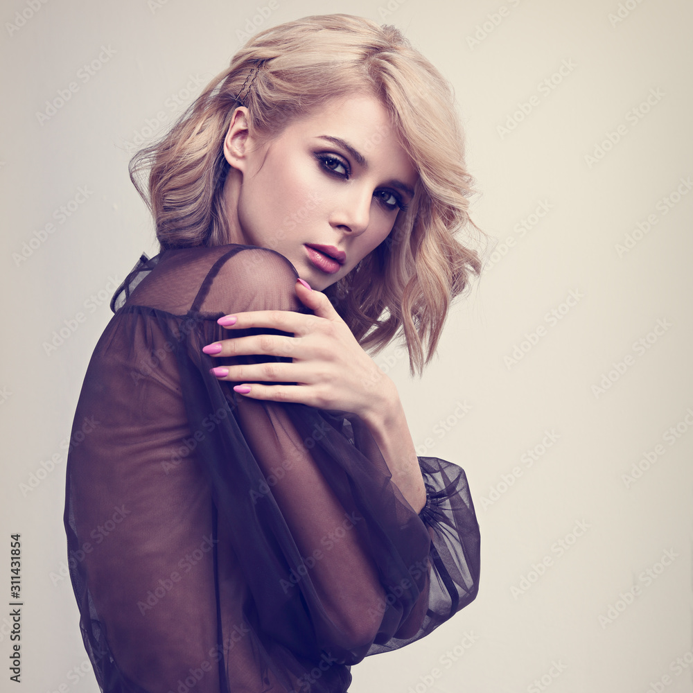 Alluring blond beautiful woman with curly short hair style posing in  fashion black dress on blue background. Closeup studio portrait. Toned  Stock Photo | Adobe Stock