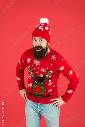 Happy new year concept. Join holiday party. Christmas eve. Winter outfit. Good vibes. Favorite winter season indoor activities. Hipster bearded man wear winter sweater and hat red background