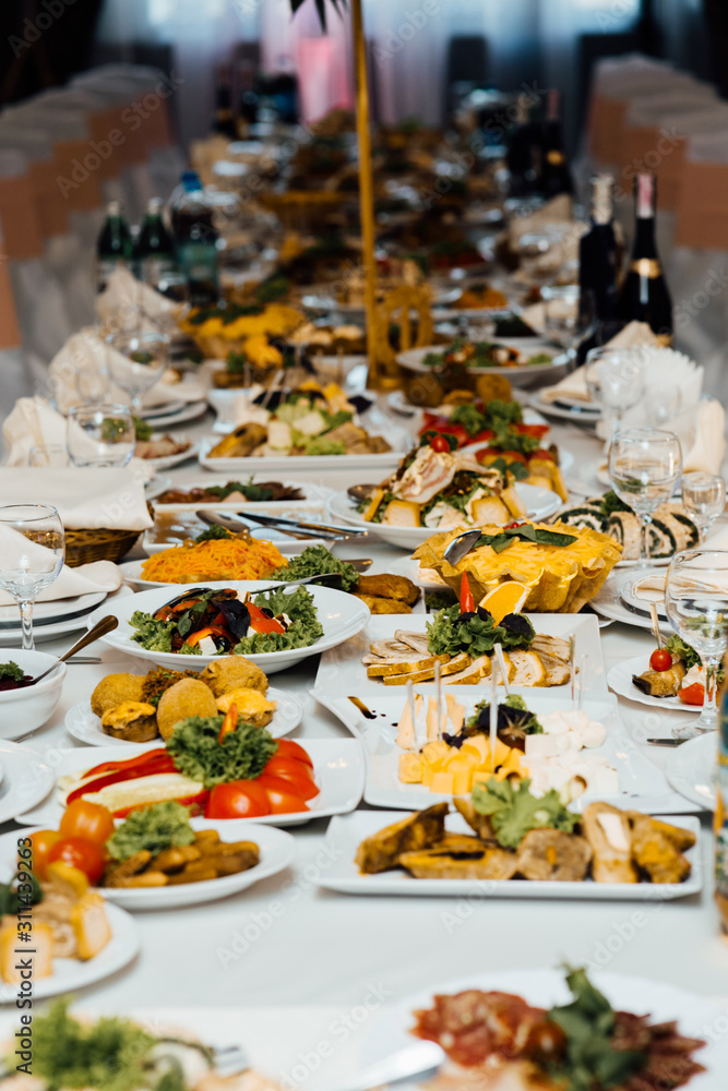 Served dishes to the table for holiday. Cutlery and food on white tablecloths in the restaurant. Design a festive Banquet. Luxurious food for guests and visitors