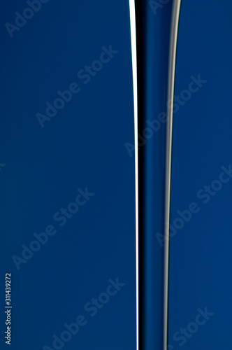 A vertical stream of water on a blue background in close-up. Abstraction.