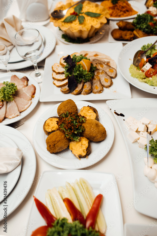 Catering service. Restaurant table with food. Huge amount of food on the table. Plates of food. Dinner time, lunch. A lot of food in a restaurant on white plates