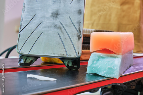 Obraz na płótnie Ski wax iron and wax bars, colored orange and teal for different temperatures, laid on top of a pair of skis. Ski base tuning concept. w salonie