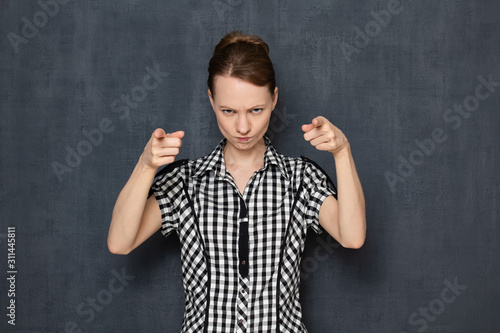 Portrait of angry girl pointing at you and accusing in bad results
