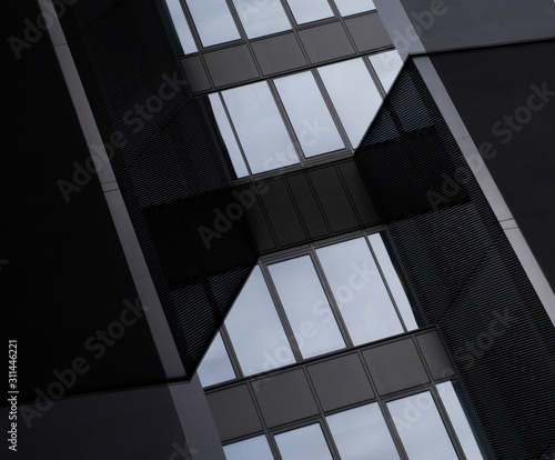 Digitally rendered image of industrial or office building fragments. Glass and metal. Wall panels and windows reflecting the sky. Abstract modern architecture background. Angular geometric structure.
