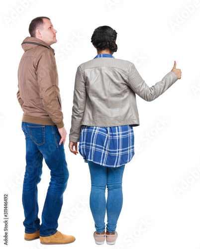 Back view of couple couple in winter jackets showing thumbs up.