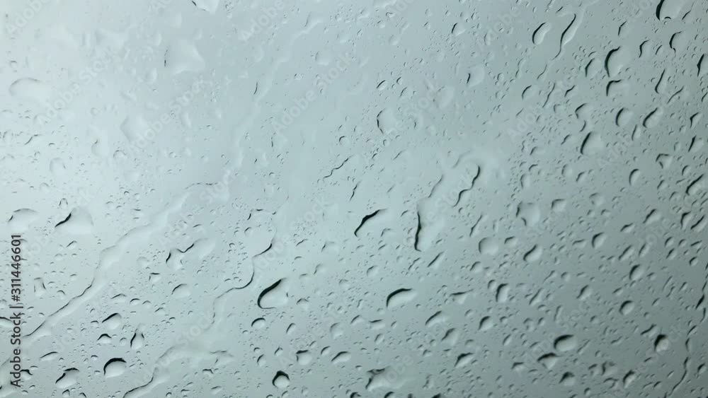 Rain is shown up close hitting and rolling down a windshield, as viewed up close from the car interior. Rain is shown up close hitting and rolling down a windshield, as viewed up close from the car interior.