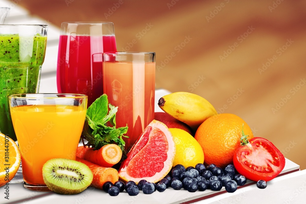 Composition of fruits and glasses of juice on blurred natural background - obrazy, fototapety, plakaty 